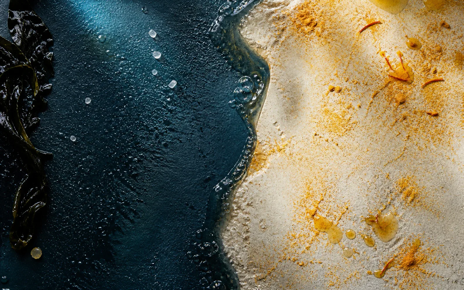 Composition de granit mouillé, sel, pierre claire et safran séparés par une rive liquide